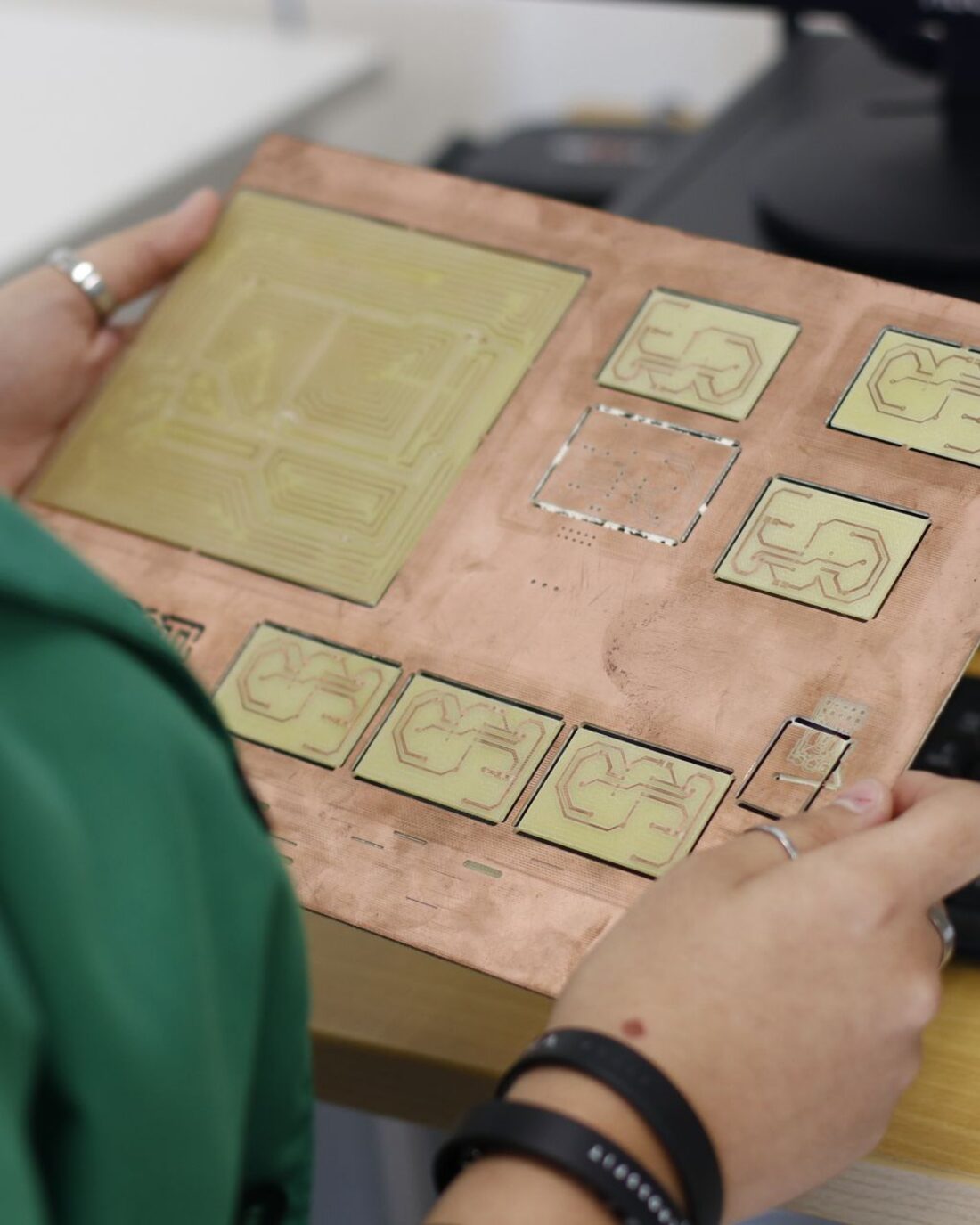Technician holding a copper-clad panel of milled prototype circuit boards.